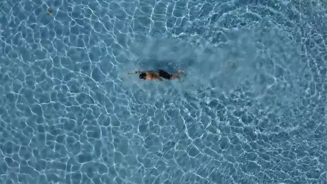 Overhead view of a swimmer in a sunlit outdoor pool